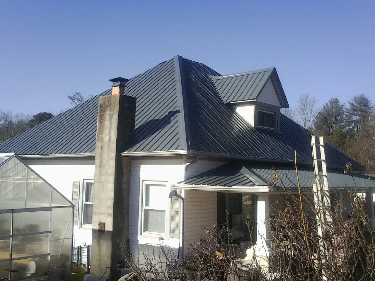 Dark blue standing seam metal roof on a white farmhouse with dormer — Slate & Tile Roof Repair by Roofing Brothers in Osceola Mills