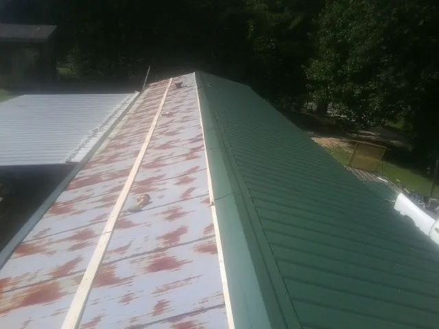 Old rusted panels beside newly installed green metal roofing — Wind Damage Roof Repair by Roofing Brothers in Osceola Mills
