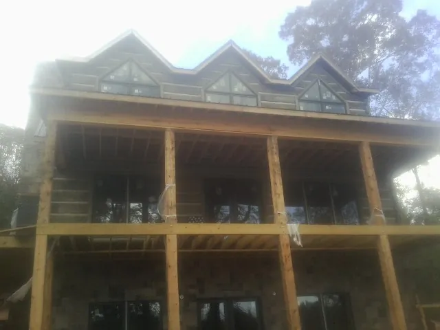 Dormers and porch framing on a large log home under construction — Roof Coating work by our crew in Osceola Mills