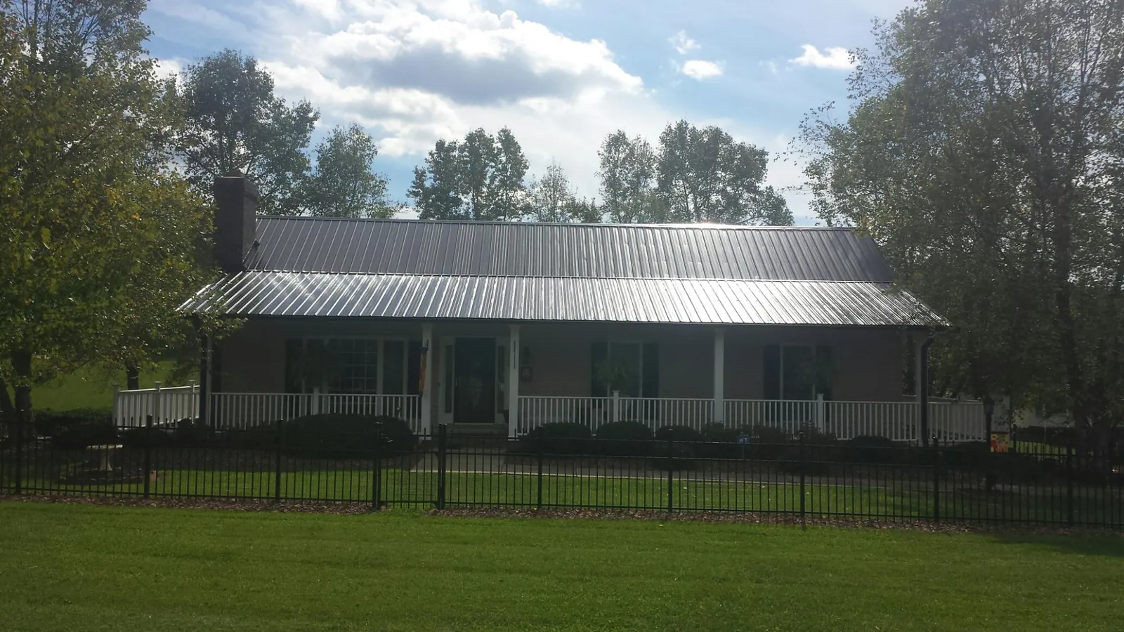 Gray metal roof on a brick ranch with a full width front porch — Gutter Guard Installation work by our crew in Osceola Mills