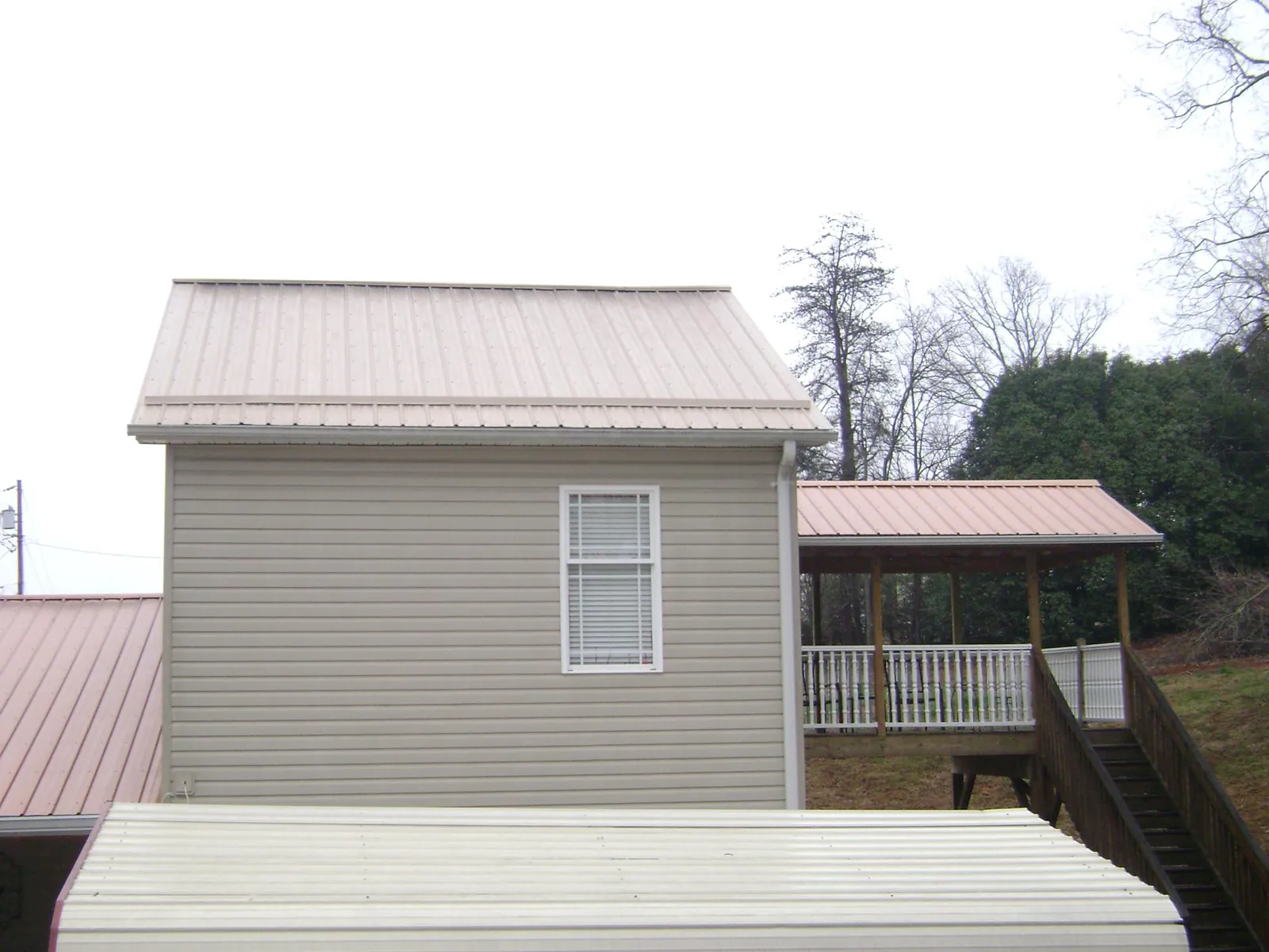 Tan metal roofs on a two story addition and attached porch, from a Roof Replacement job in Osceola Mills