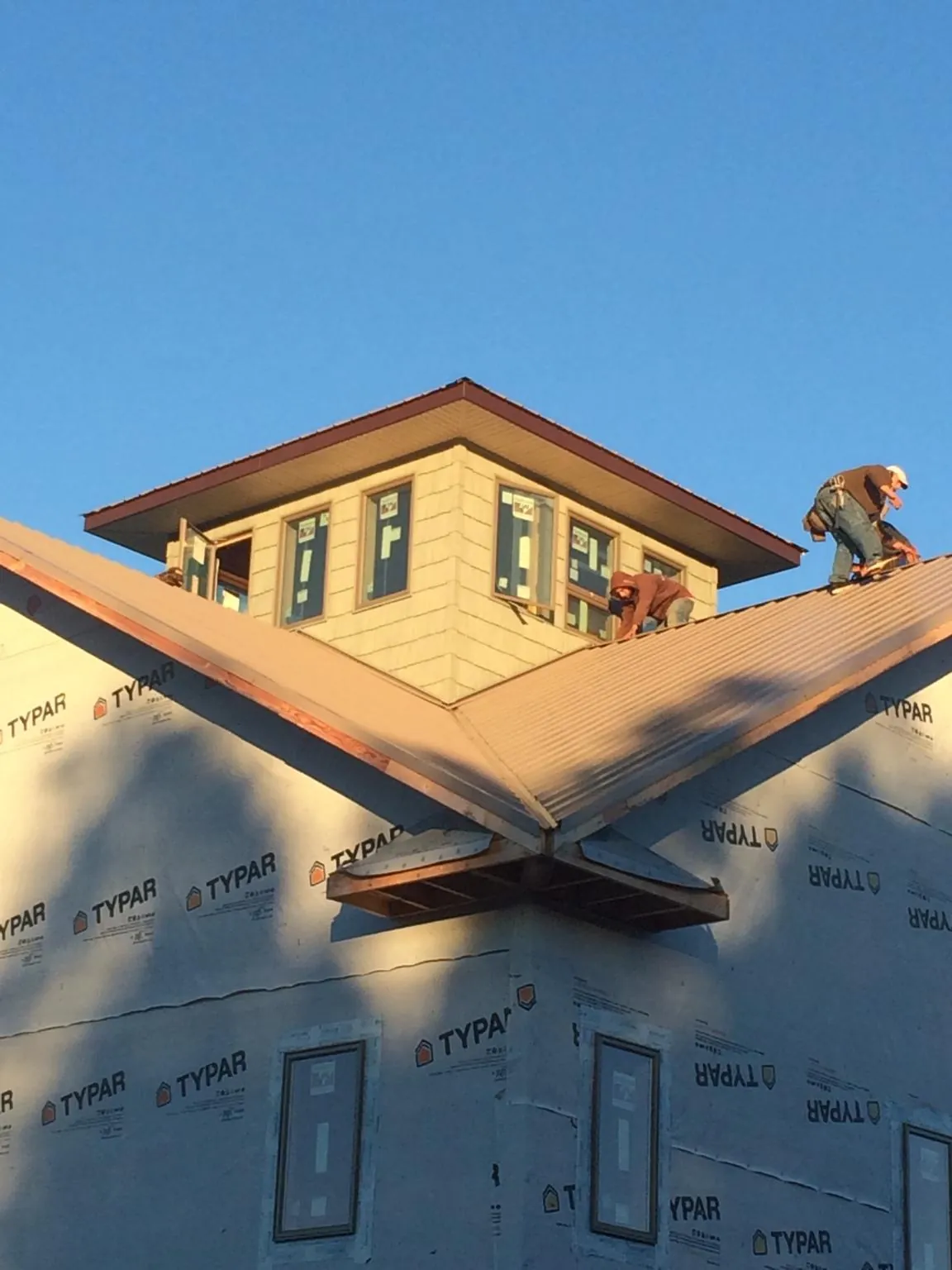Roofers working around a rooftop cupola on a new metal roof at sunset — Roof Waterproofing in Osceola Mills by Roofing Brothers